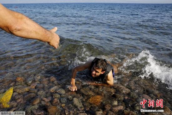 当地时间9月17日，希腊莱斯博斯岛一名当地人帮助跳下船游到精疲力尽的叙利亚难民。