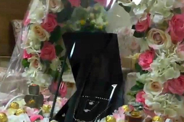 花束中间还摆放着珠宝，这可能是送给新娘的礼物，她被允许留在监狱中度蜜月。（网页截图）